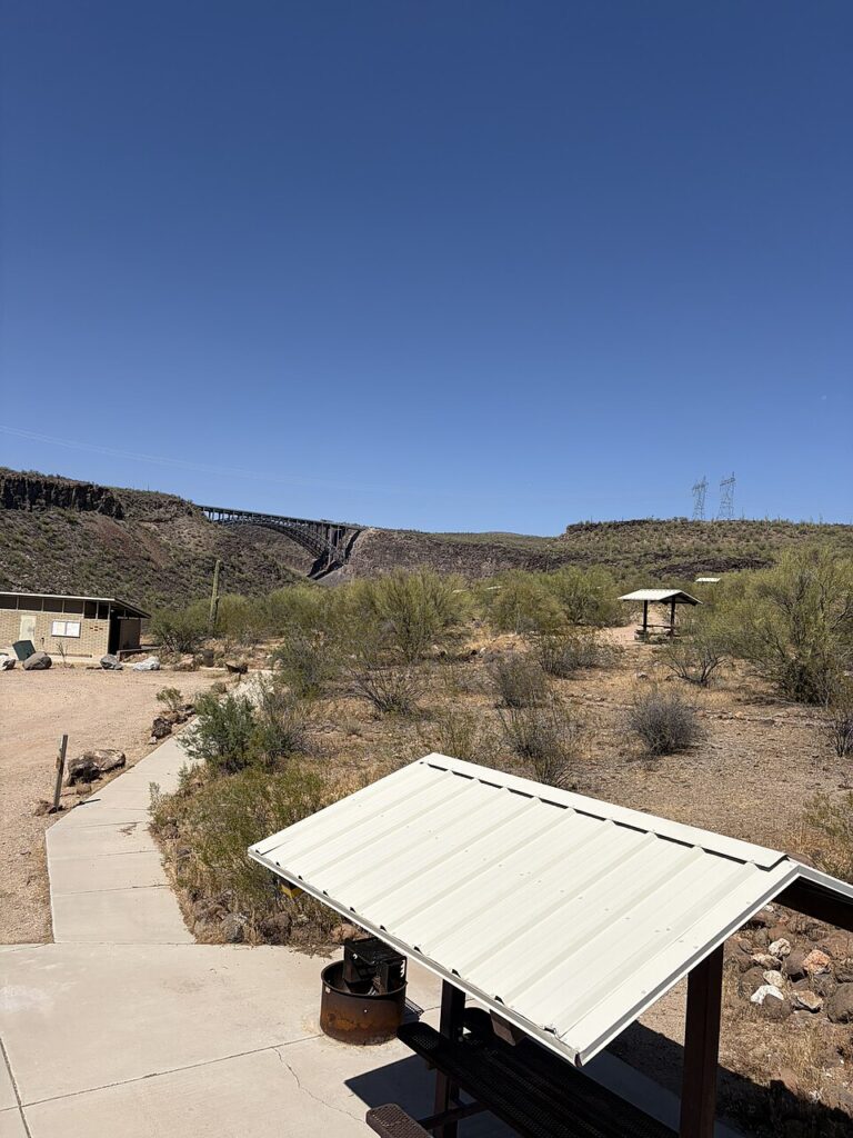 Burro Creek campground picnic shelter and arid hills with distant bridge in Arizona