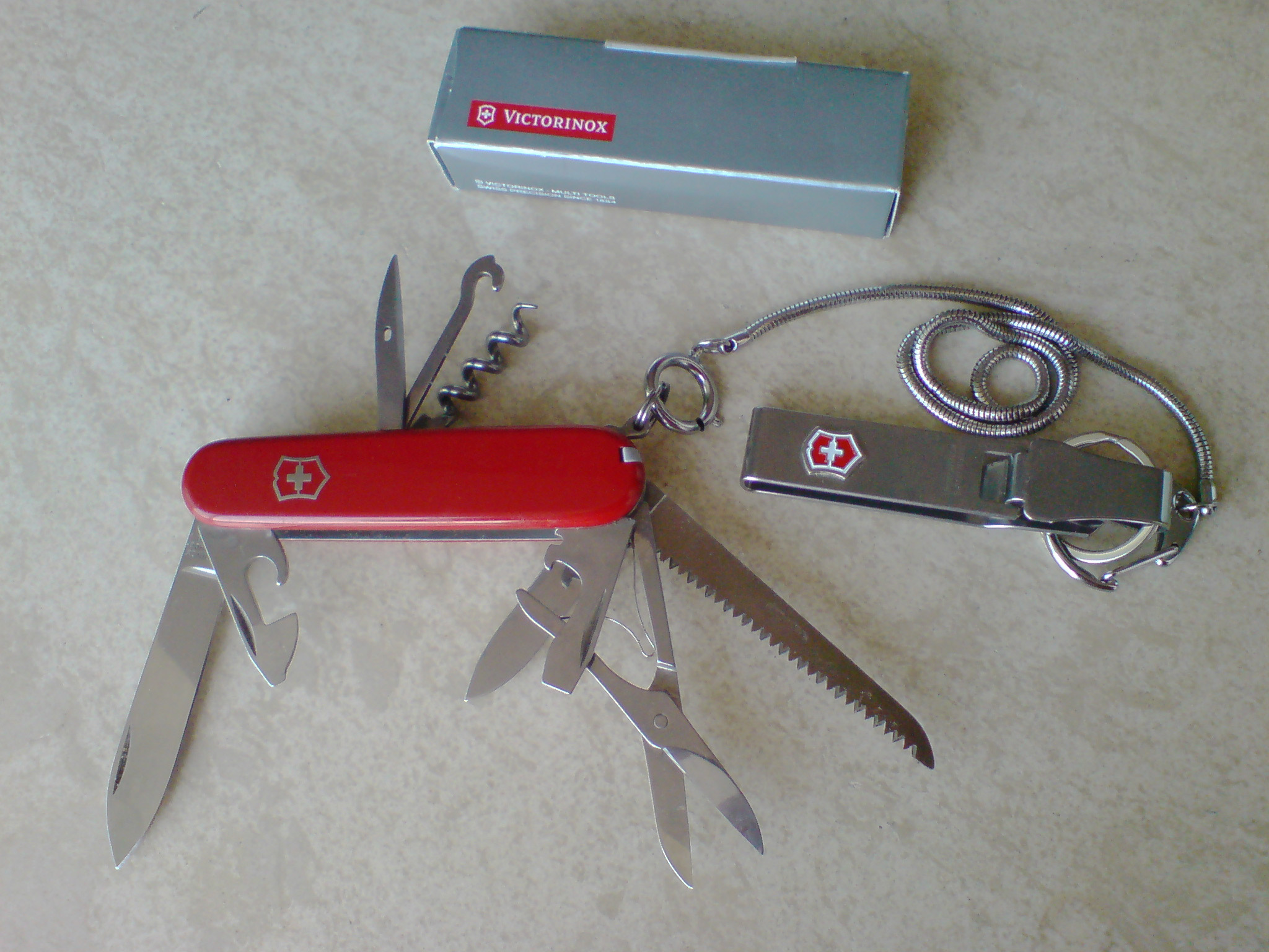 Victorinox Huntsman red Swiss Army knife with scissors and wood saw opened; separate chain accessory shown